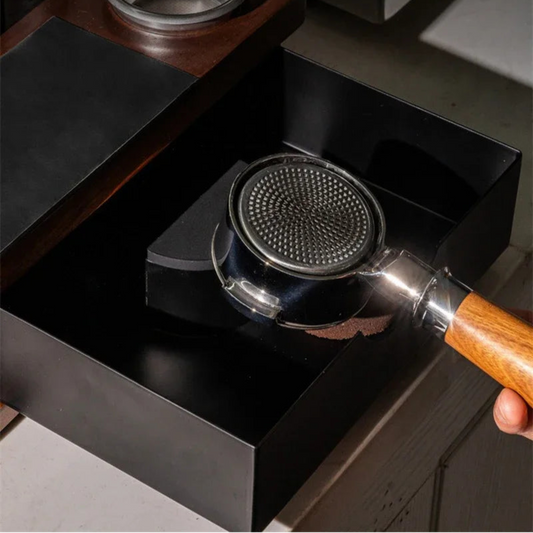 Stainless steel coffee filter with wooden handle on a black stovetop