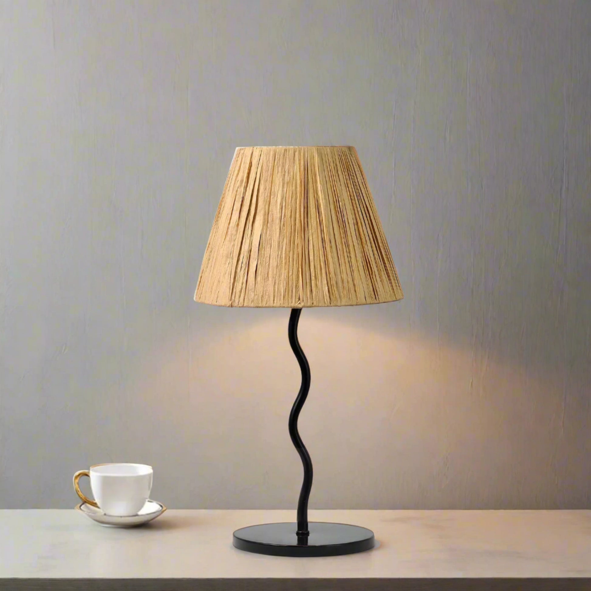 Table lamp with pleated shade on a white surface next to a gray sofa.