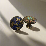 Two decorative cabinet knobs with intricate designs on a plain background