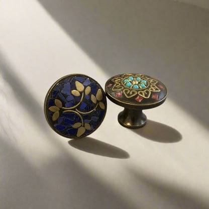 Two decorative cabinet knobs with intricate designs on a plain background