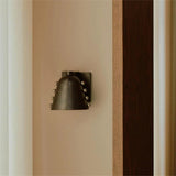 Decorative wall sconce mounted on a beige wall with a wooden panel.