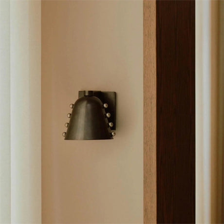 Decorative wall sconce mounted on a beige wall with a wooden panel.