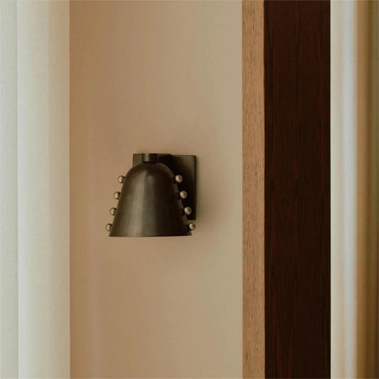 Decorative wall sconce mounted on a beige wall with a wooden panel.