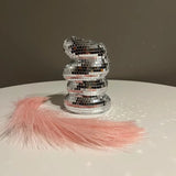 Stack of silver disco balls with pink tassels on a reflective surface