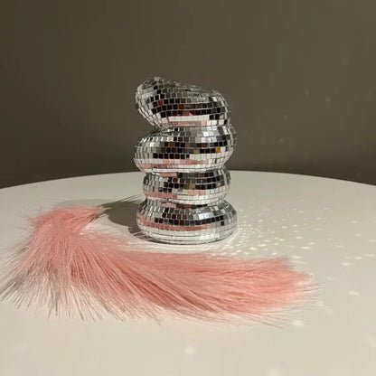 Stack of silver disco balls with pink tassels on a reflective surface