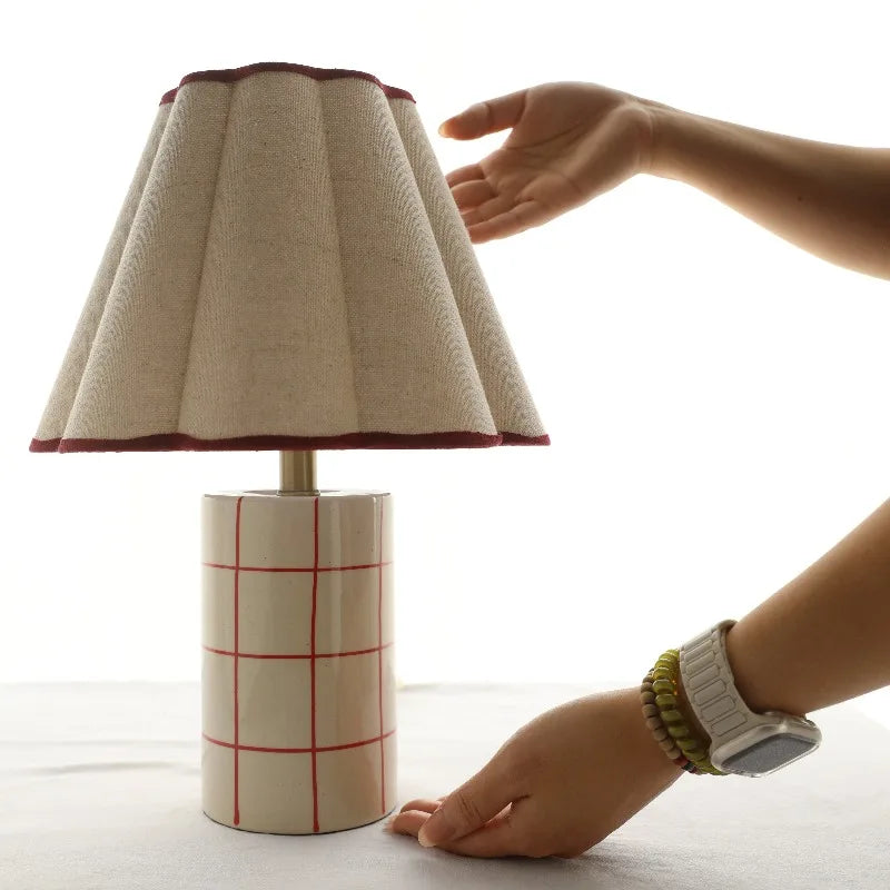 Person adjusting a lamp with a fabric shade on a white background