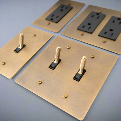 Brass light switch plates with black outlets on a white background,