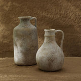 Two rustic ceramic jugs against a textured brown background
