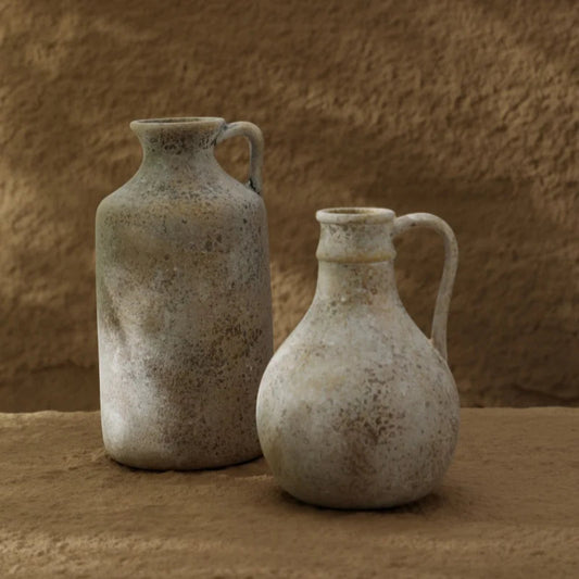 Two rustic ceramic jugs against a textured brown background
