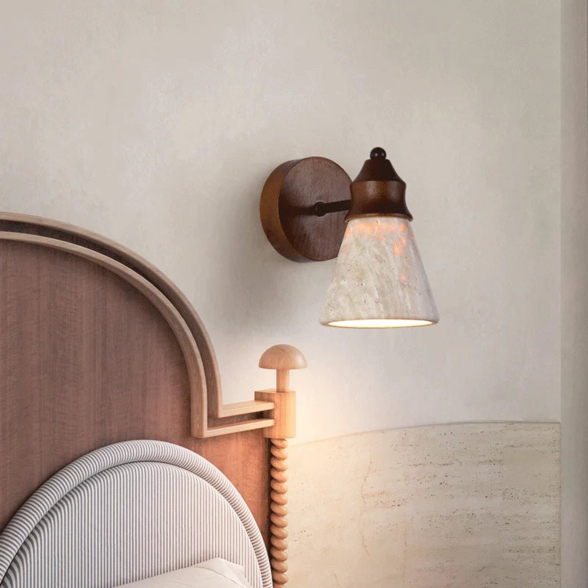 Wall-mounted lamp with a wooden headboard and bed in the background