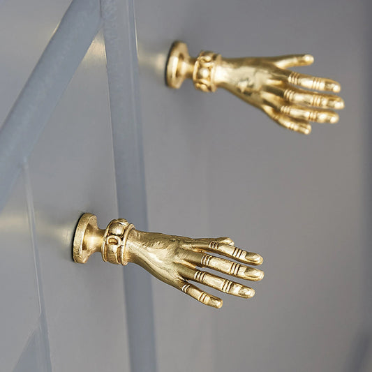 Gold hand-shaped door handles on a gray surface