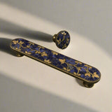 Decorative handle with blue and gold design on a plain background