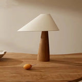 Table lamp with wooden base and white shade on a wooden table.
