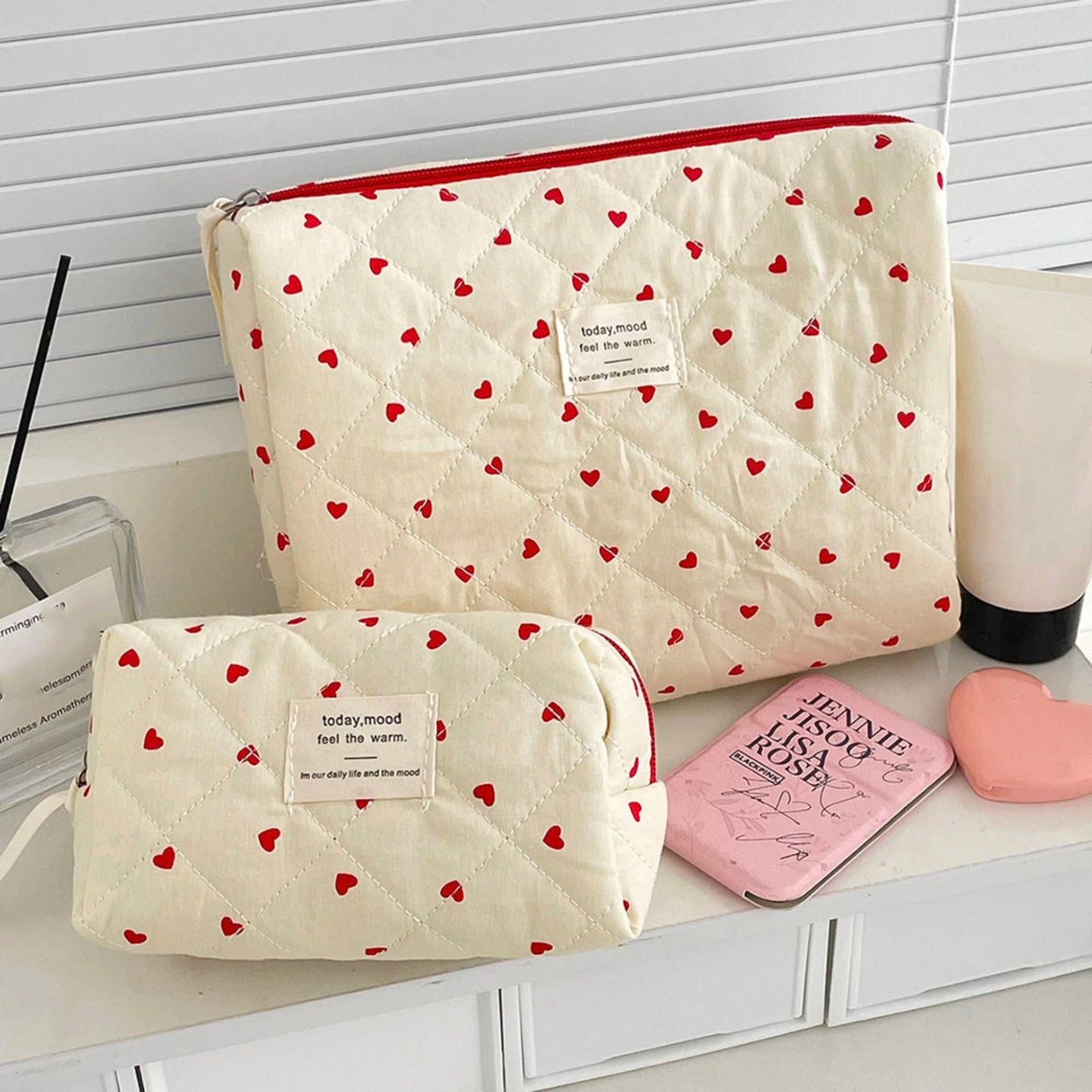 Two cream-colored pouches with red heart patterns on a surface.