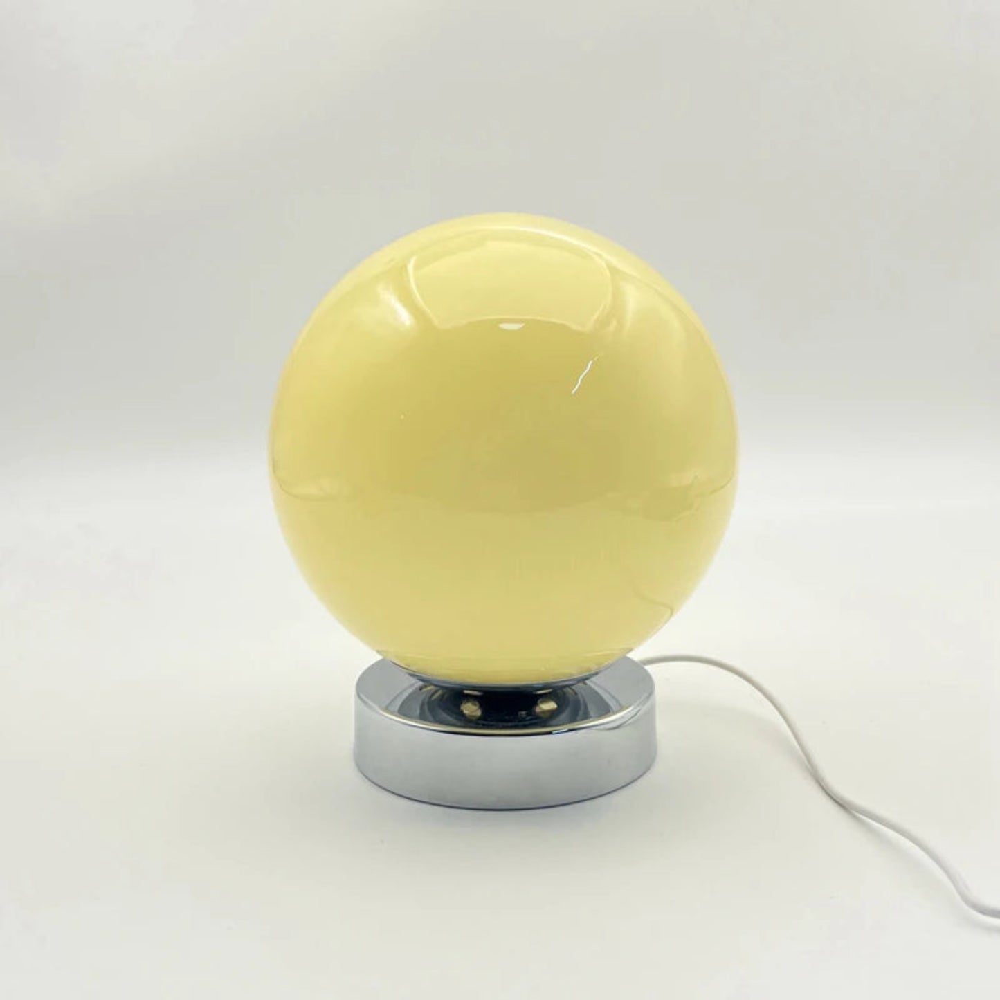 Yellow spherical lamp with a metallic base on a white background
