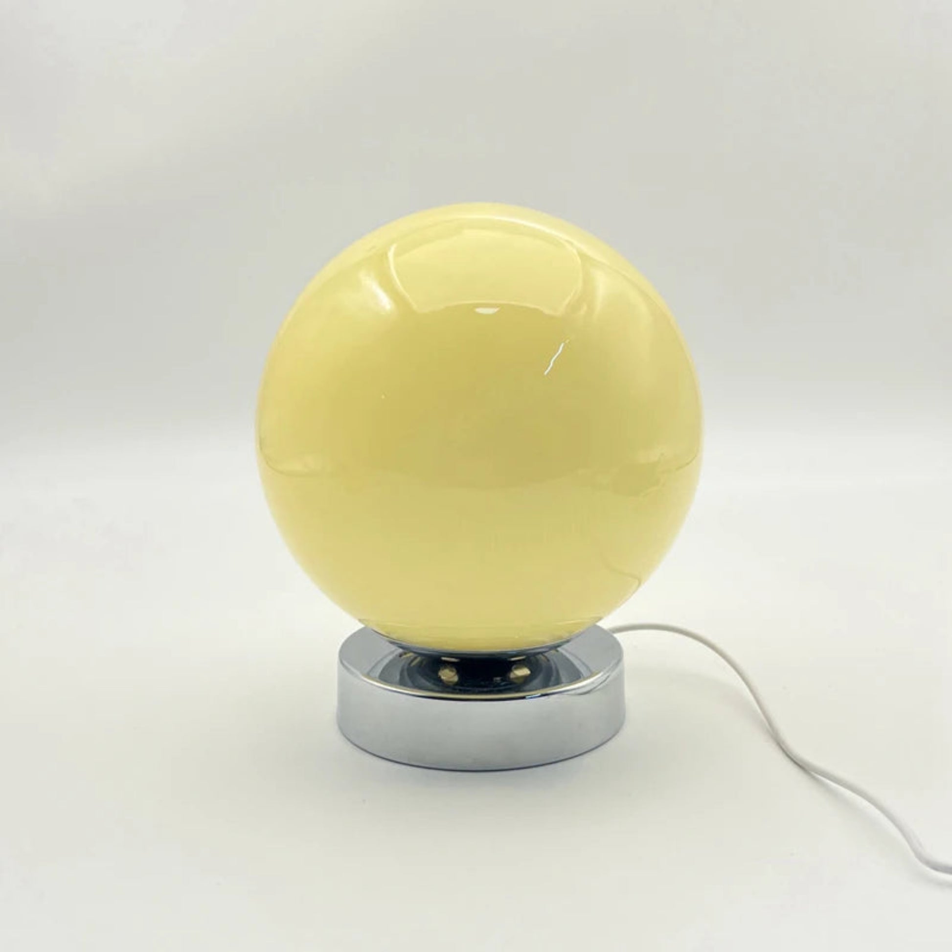 Yellow spherical lamp with a metallic base on a white background