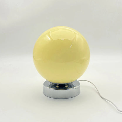 Yellow spherical lamp with a metallic base on a white background
