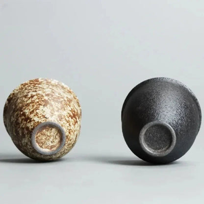 Two ceramic pots, one with a textured brown surface and the other black, on a light gray background.
