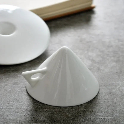 White ceramic funnel on a dark surface with a book in the background