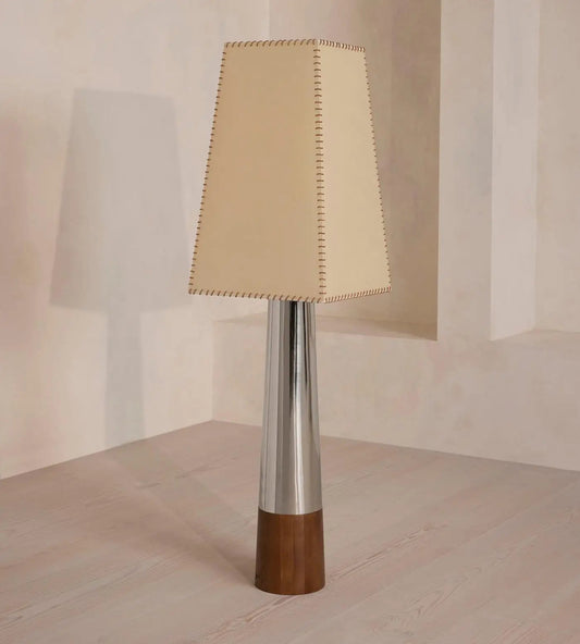 floor lamp with a beige fabric shade, silver cylindrical body, and wooden base on a neutral background.
