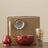 Tea-making set with a red teapot, strainer, and glass container on a beige background