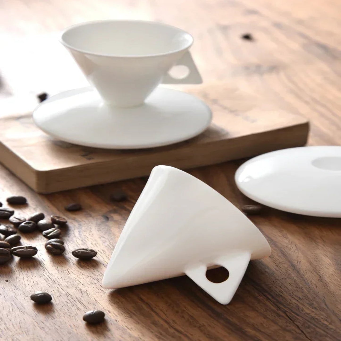 White ceramic filter on a wooden surface with coffee beans