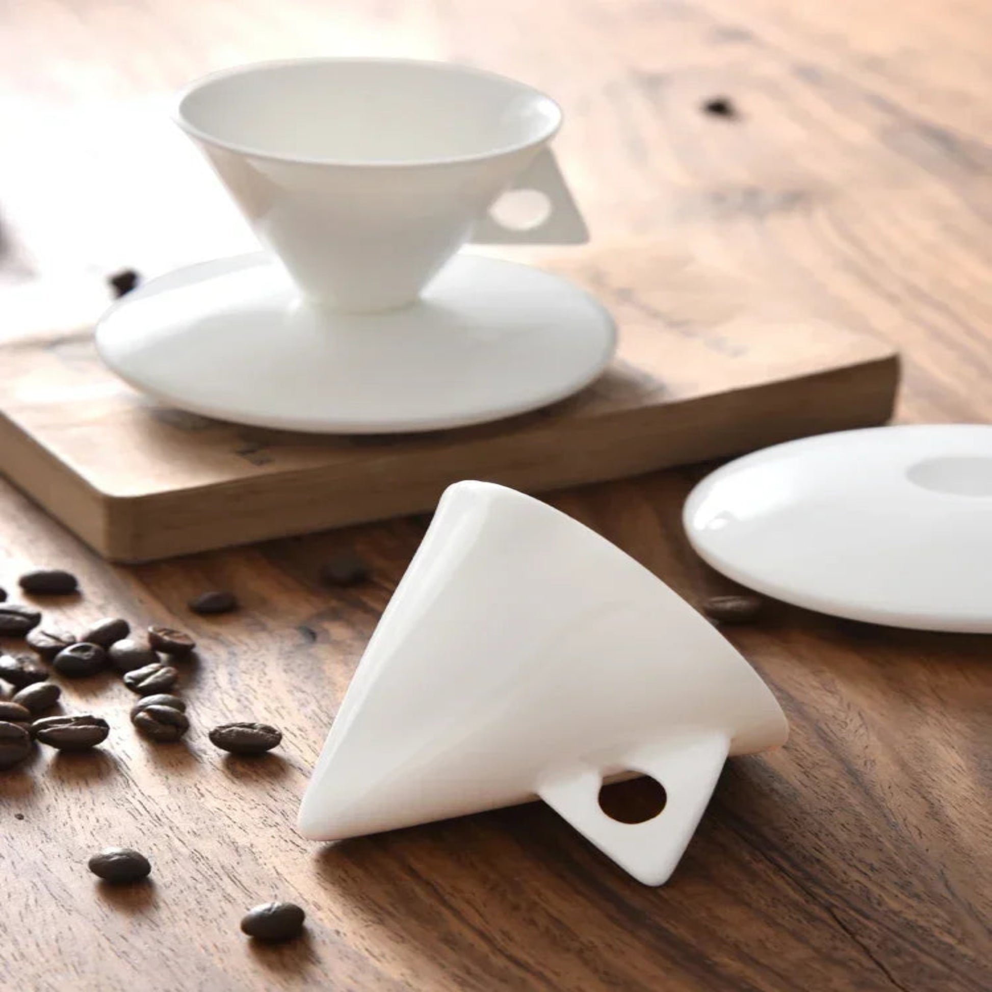 White ceramic filter on a wooden surface with coffee beans