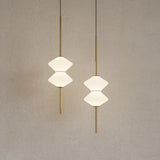 Two geometric pendant lights hanging against a plain wall.