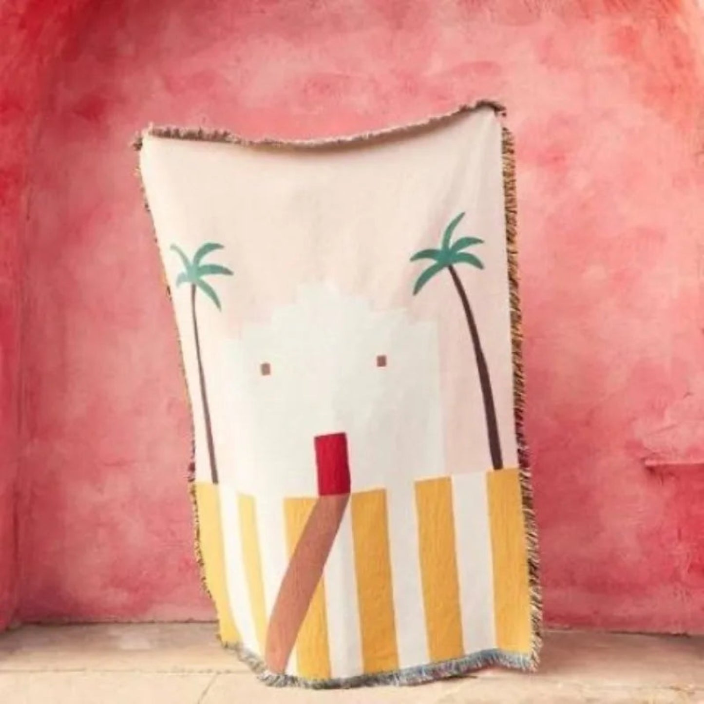 Decorative throw blanket with palm tree and striped design on a pink background