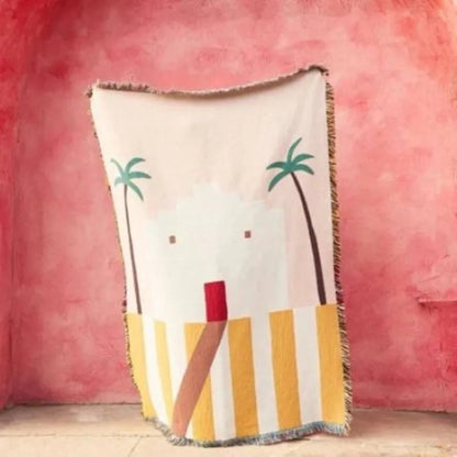 Decorative throw blanket with palm tree and striped design on a pink background