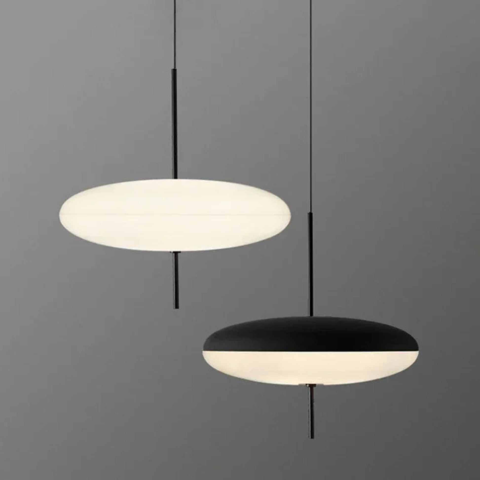 Two pendant lights, one white and one black, on a gray background