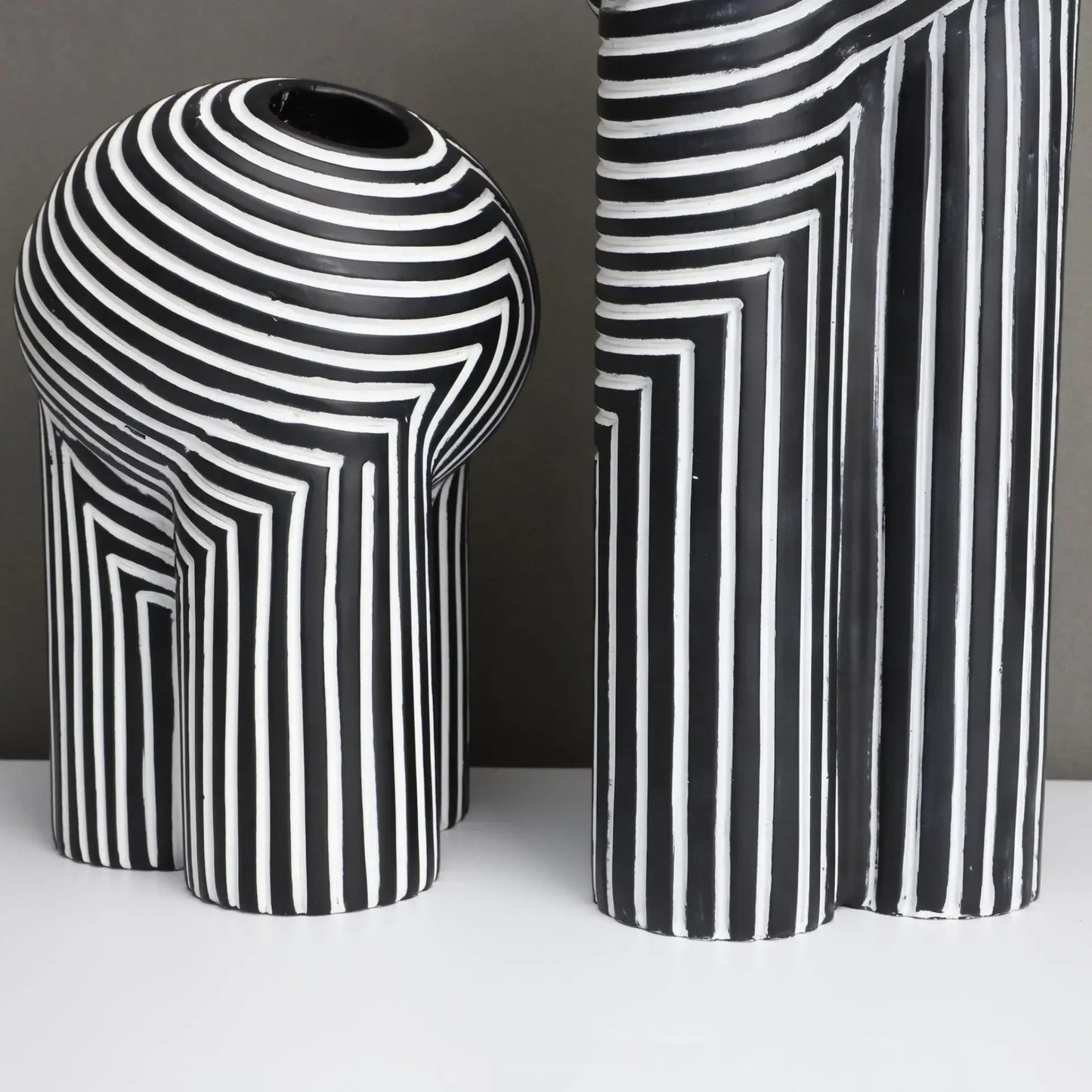 Two black and white striped vases on a neutral background