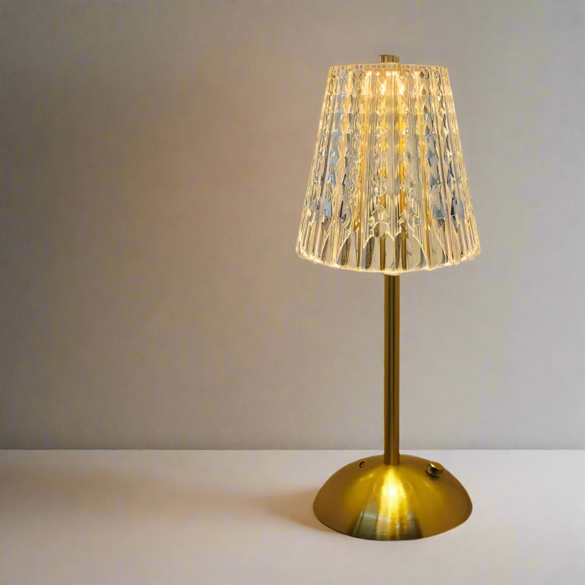 Decorative table lamp with a gold base and ribbed glass shade on a neutral background

