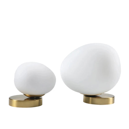 Two white spherical objects with gold bases on a light gray background