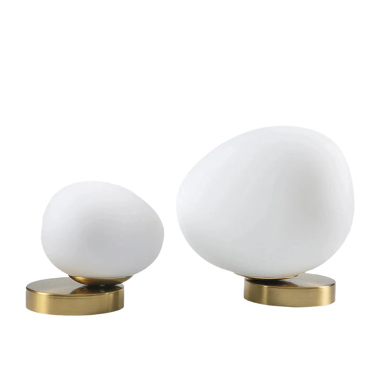 Two white spherical objects with gold bases on a light gray background