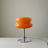 Orange table lamp on a wooden surface with decorative items in the background
