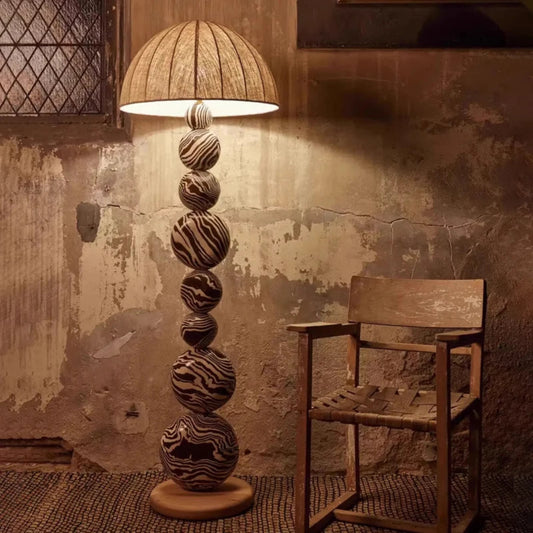 Decorative floor lamp with spherical design next to a wooden chair against a textured wall.