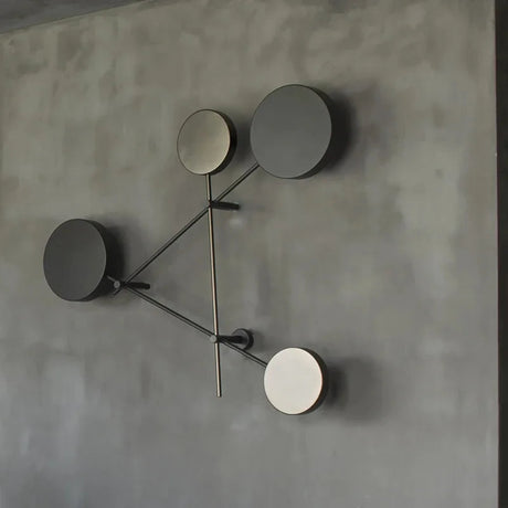 Modern wall clock with four circular faces on a gray wall