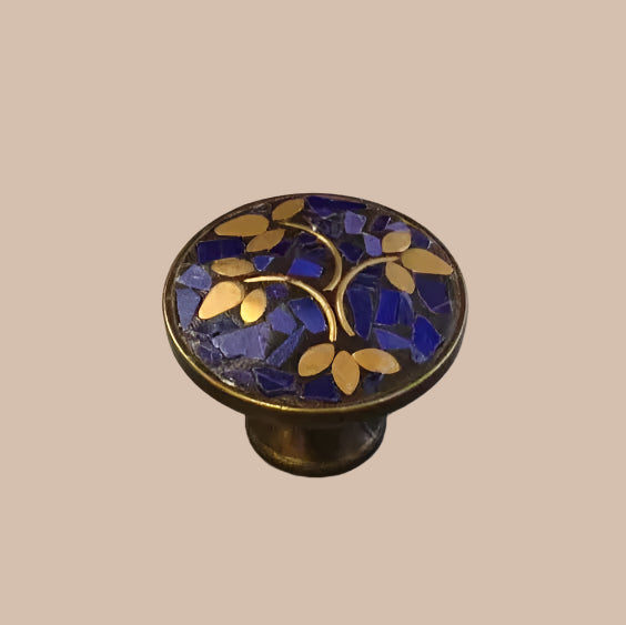 Decorative cabinet knob with blue and gold leaf pattern on a gray background