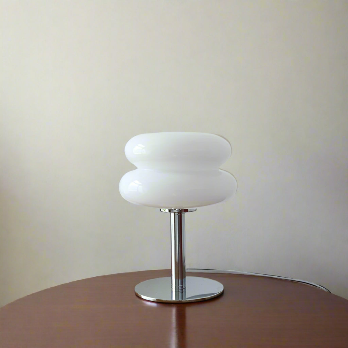 White table lamp on a wooden surface with decorative items in the background