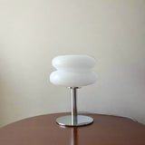 White table lamp on a wooden surface with decorative items in the background