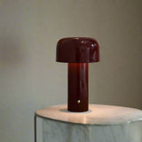 Mushroom table lamp on a wooden surface with books and a framed picture in the background