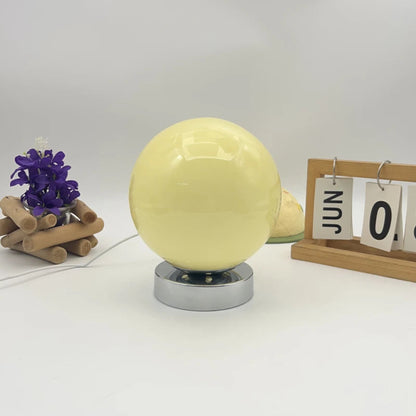 Yellow crystal ball on a stand with decorative items on a white background