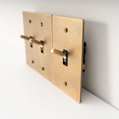 Gold wall switch plate with two toggle switches on a white background
