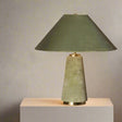Green table lamp with a textured base on a dark surface against a neutral background

