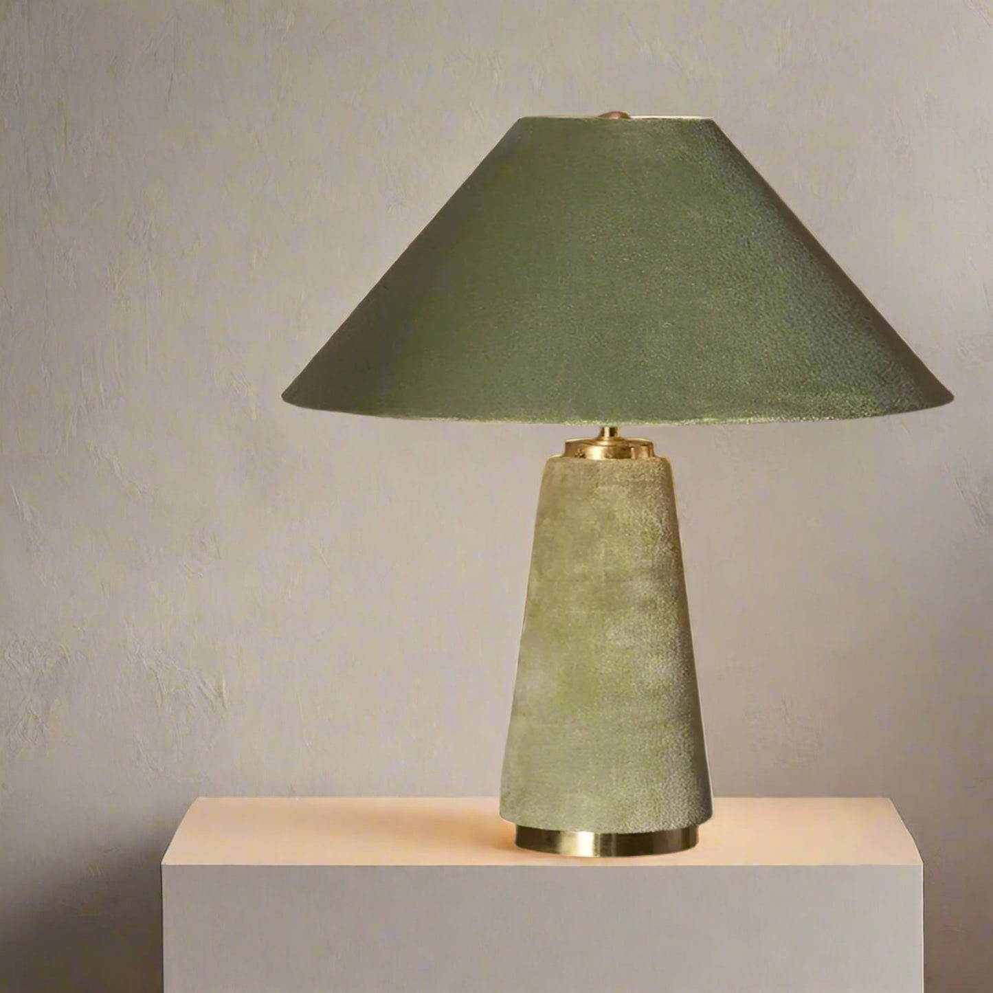 Green table lamp with a textured base on a dark surface against a neutral background

