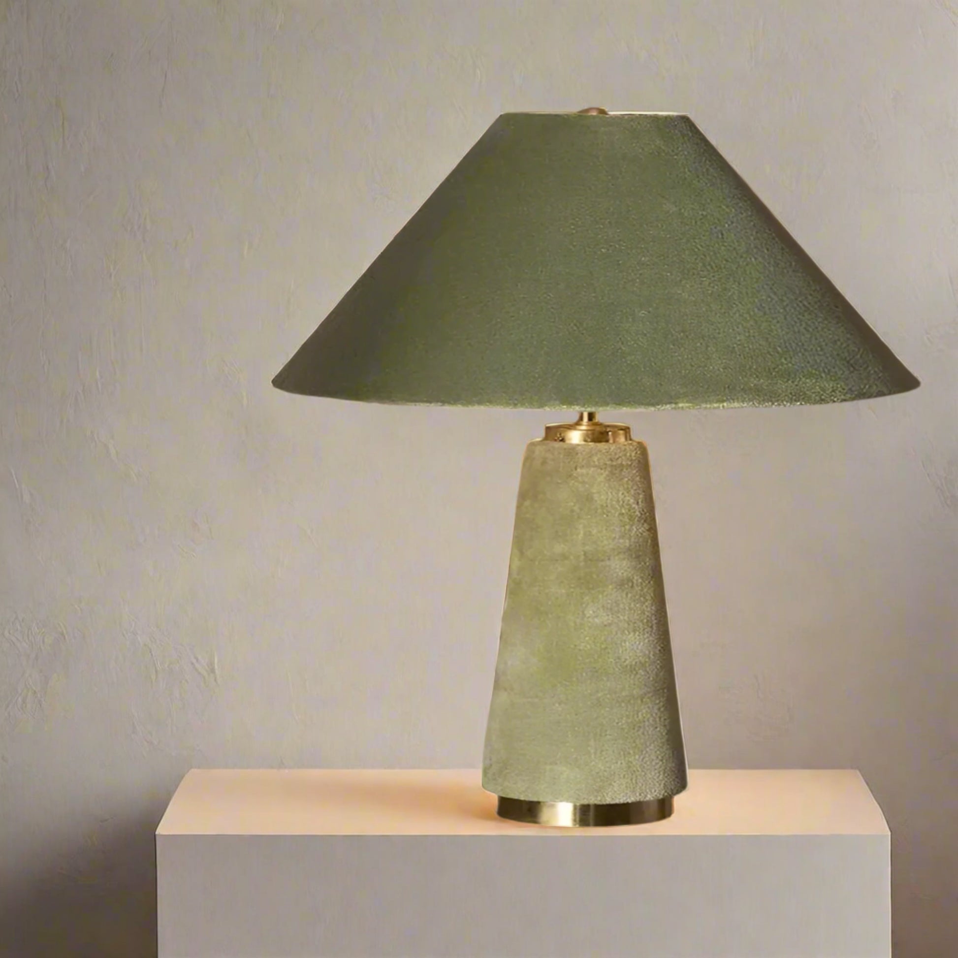 Green table lamp with a textured base on a dark surface against a neutral background


