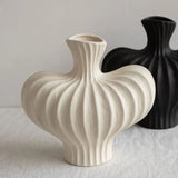 Two ceramic vases, one white and one black, on a light surface with a neutral background.