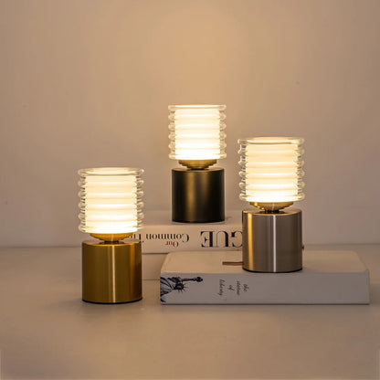 Three small table lamps with ribbed glass shades on books against a neutral background