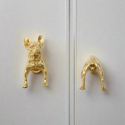 Gold dog-shaped door handles on a white cabinet.
